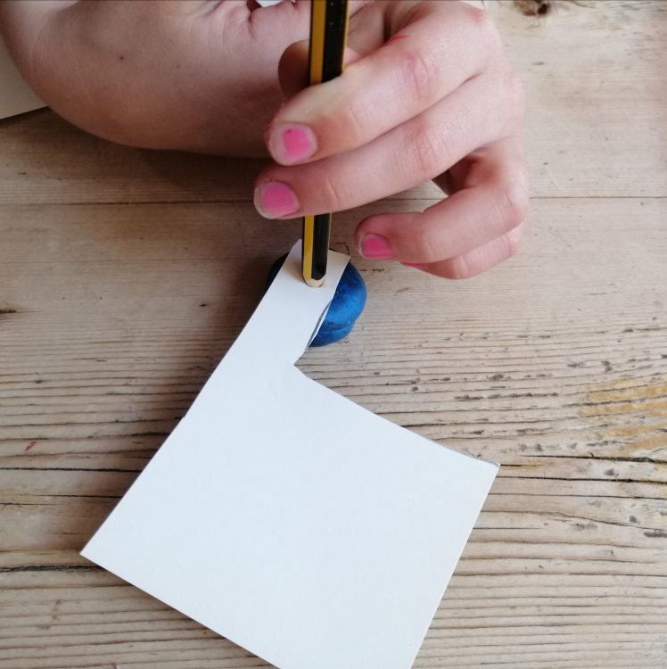Making a hole in a piece of card using a pencil and modelling clay