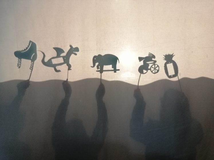 A view of 5 animal shadow puppets that children are holding up