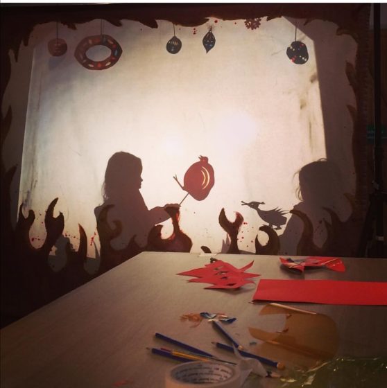 A screen shows two children in shilouetter making shadow puppets