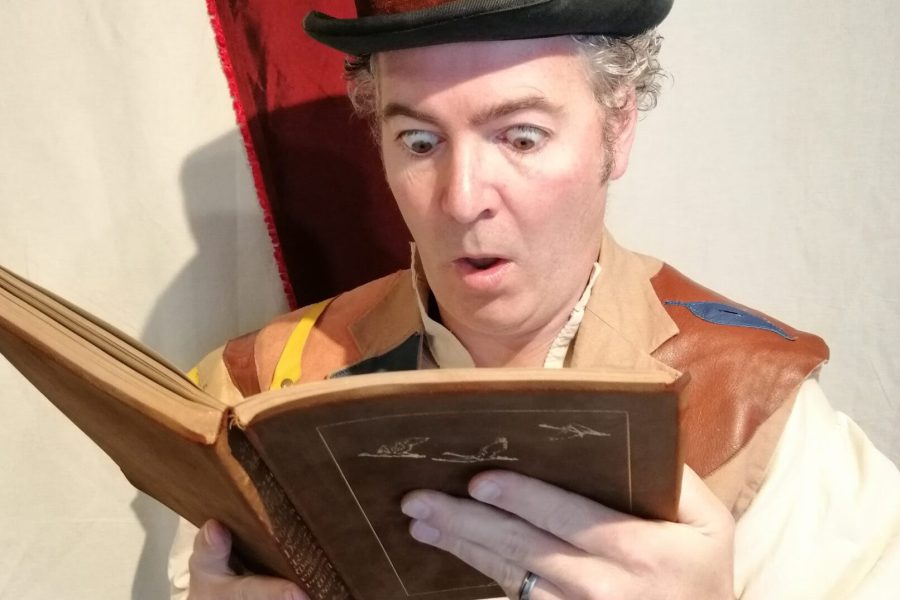 Photo of Mark reading from book. His eyes are wide in excitement