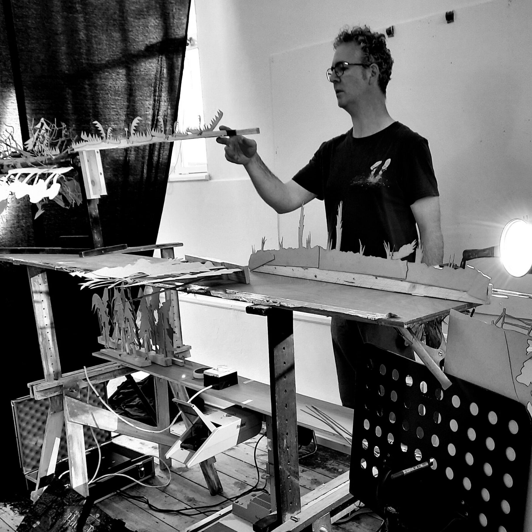 a black and white image of Mark behind a table operating shadows and lights