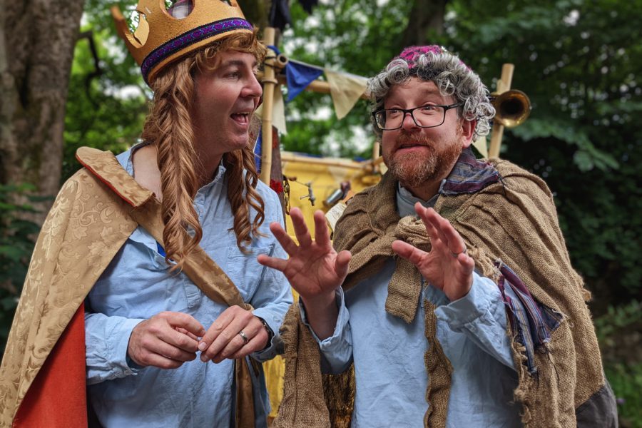 Two male actors telling a story, one dressed as an old wise woman, the other as a queen