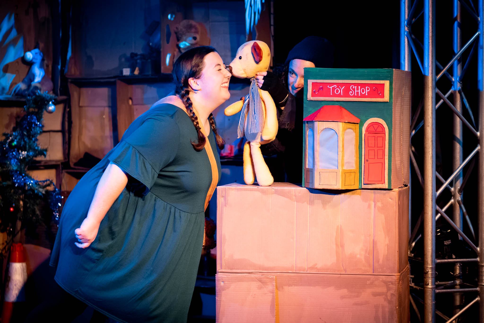 An actor who is pretending to be a small girl rubs noses with her beloved teddy