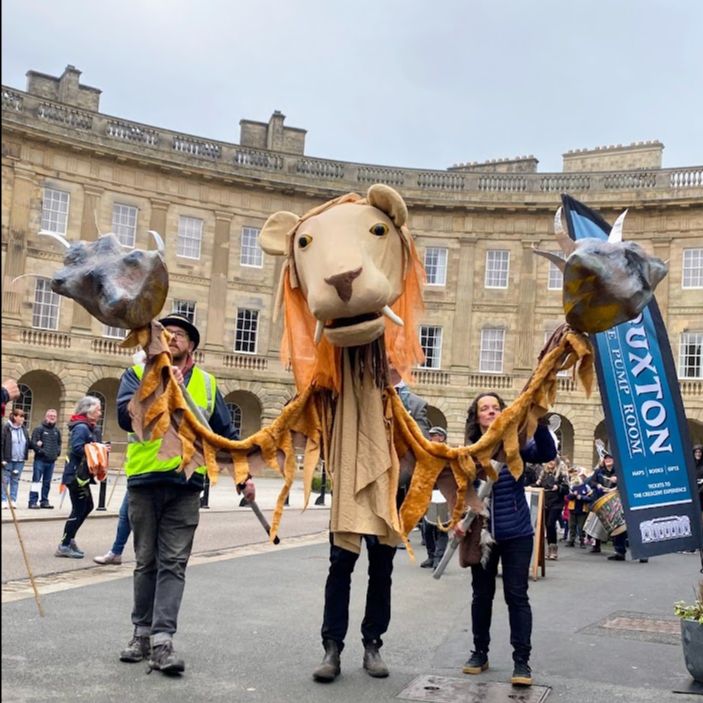 3 puppeteers parade with a big lion puppet through the streets of Buxton