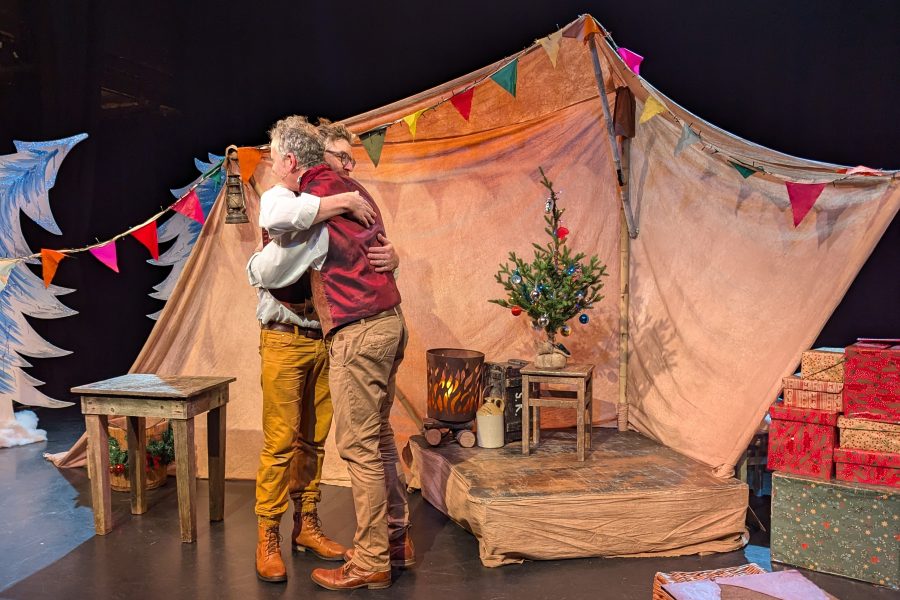 In their show The Night Before The night before Christmas to male characters are hugging on stage. There are presents, bunting and a little chritsmas tree onstage.