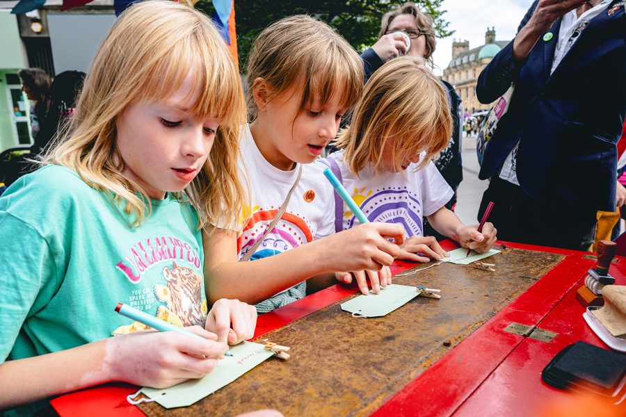 Three children write there hopes and dreams on labels at a desk