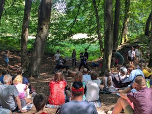 In a woodland audience members look on as children act out a scene from their story