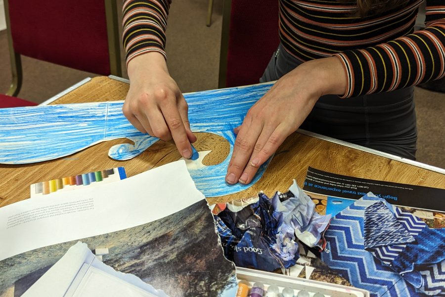 A young person is getting creative and the table is full of craft materials, coloured pastels and magazines cuttings