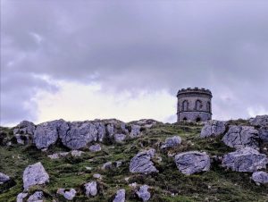 The back view of Solomens temple. A rocky outcrop of rocks blocks the full view of the tower, so you see just the top of it againsts a grey sky