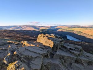 At the top of Win Hill looking out over the vast landscape. it is a coild january day and the sun is shining and the sky is blue