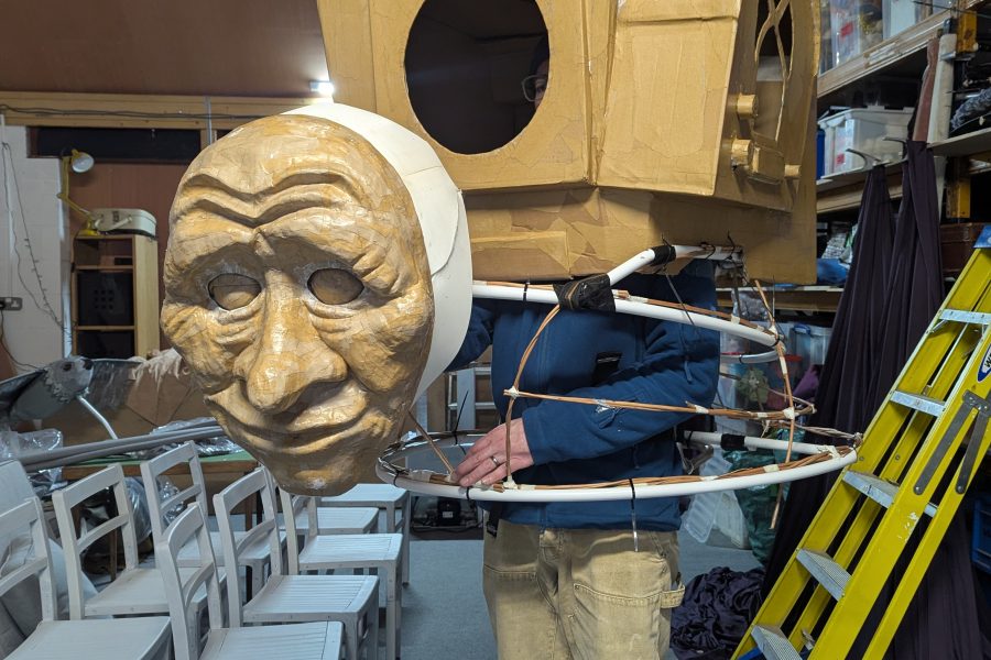 This is a working progress of a very large walkabout puppet. A person stands inside the body section and is hidden by an oversized backpack