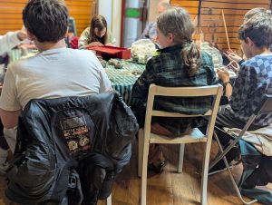 We see the backs of participants sat at a table and exploring the materials before them.