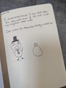 A journal and the person has drawn a cartoon character with a big tummy and a top hat. they have written words and it says "I discovered that i can like the artwork even if its not what my original idea was."