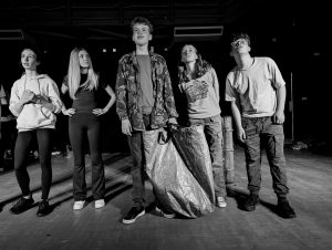 A group of young people are stood together on stage looking out to the audience