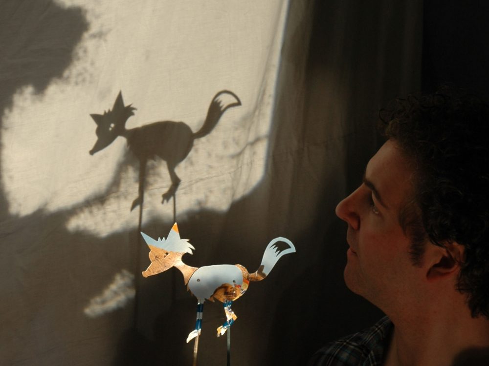 puppeteer holding a fox shadow puppet