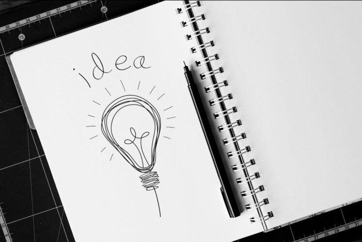 A sketch book with a lightbulb drawn on a page with the word "Idea" written at the top of the page
