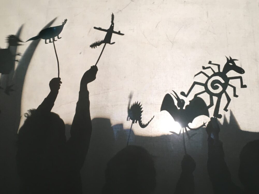 Shadows of children holding up their monster style shadow puppets that they designed